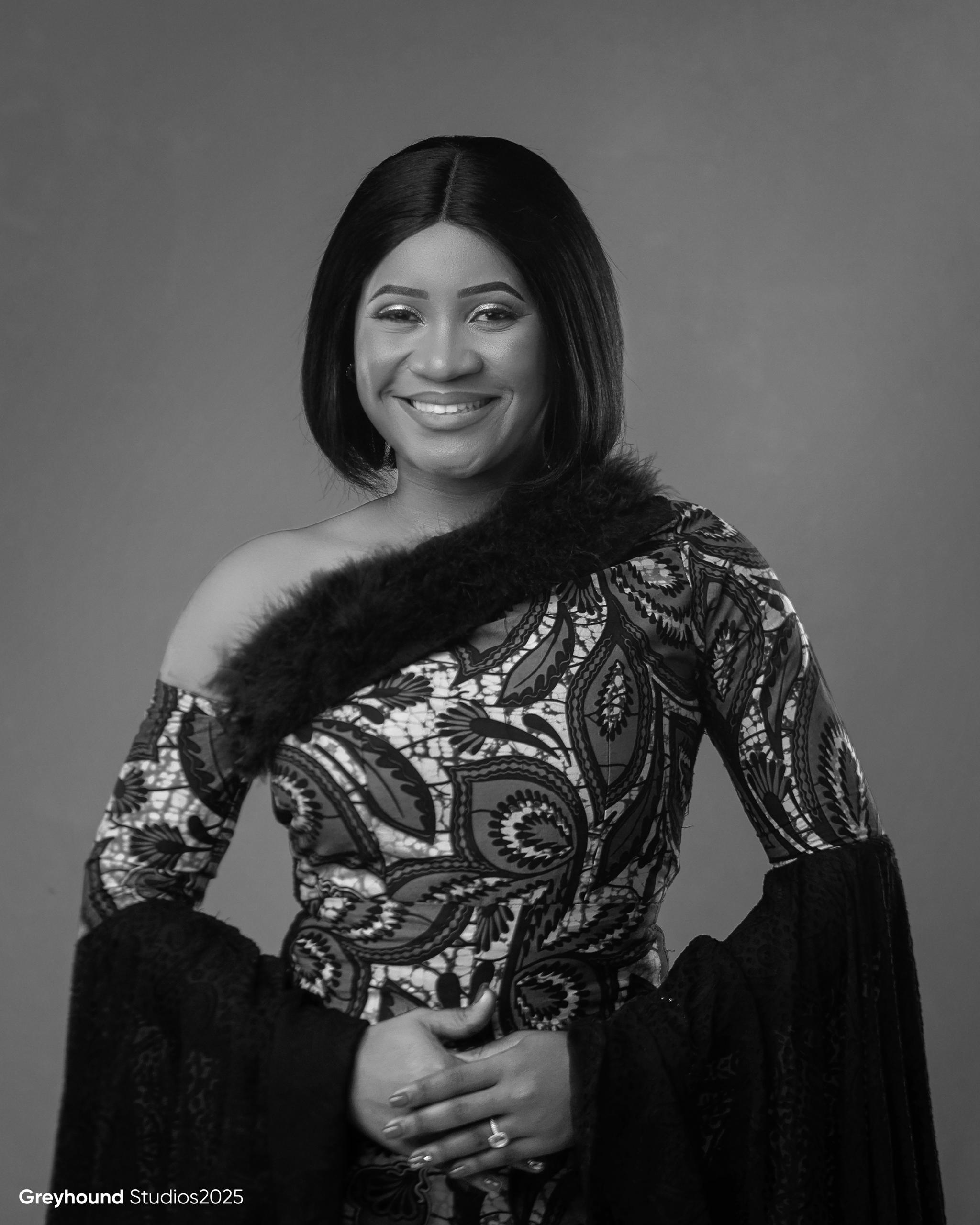 Black and white portrait of Tendai Makoni smiling warmly in African print dress with fur trim